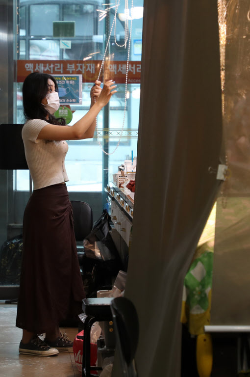 Woman closing her handmade jewelry stall after a day of selling at Namdaemun Market